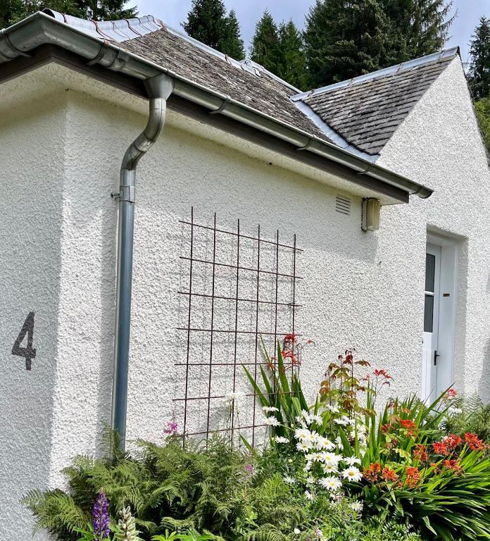 a white house with a bunch of flowers at 4 Balvaig Cottage, Strathyre in Stirling