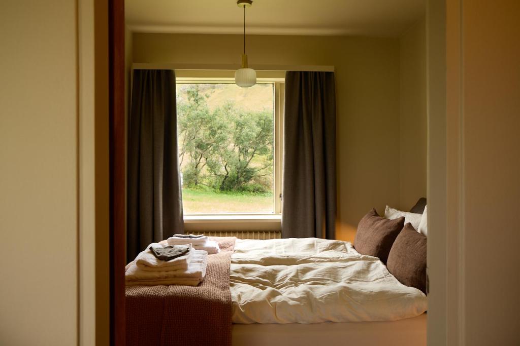 a bedroom with a bed in front of a window at Eyri Farm in Kjósahreppur