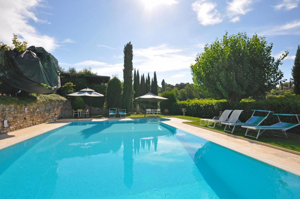 a large blue swimming pool with chairs and umbrellas at Poggiluglio by PosarelliVillas in San Gimignano