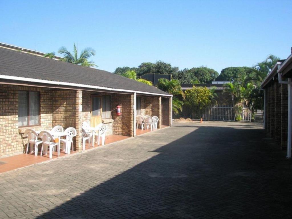 a brick building with chairs and tables on a patio at Flamboyant Apartments in St Lucia