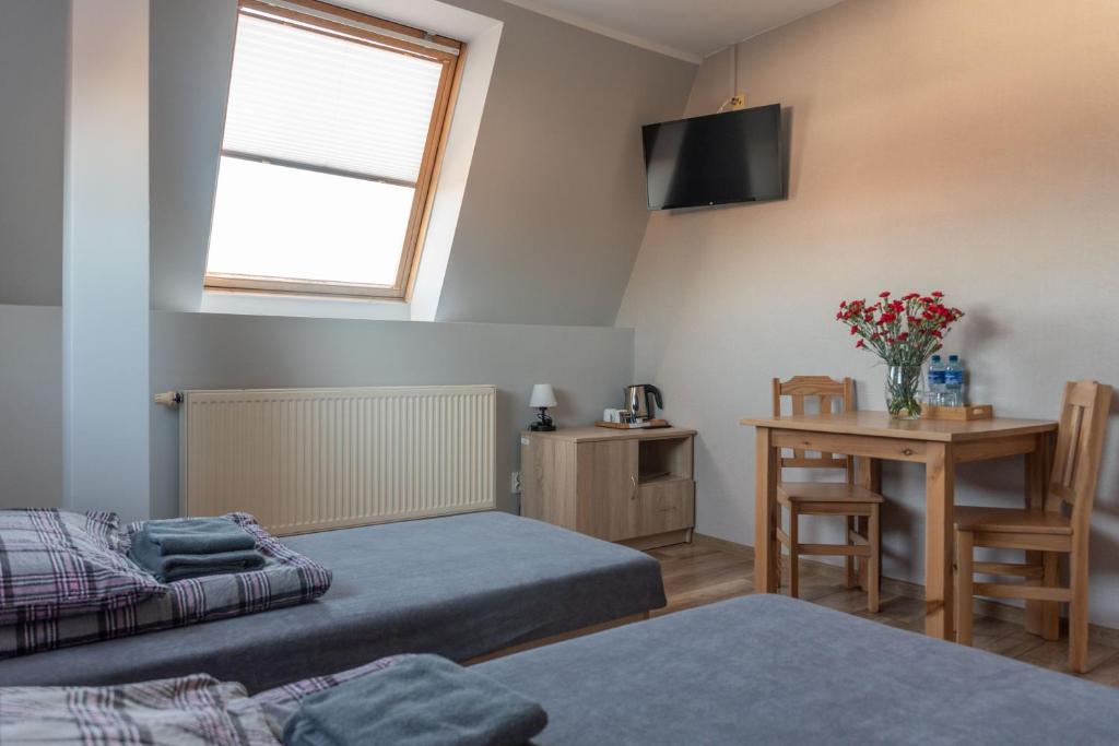 a bedroom with two beds and a table and a window at Noclegi GCK Biała in Biała