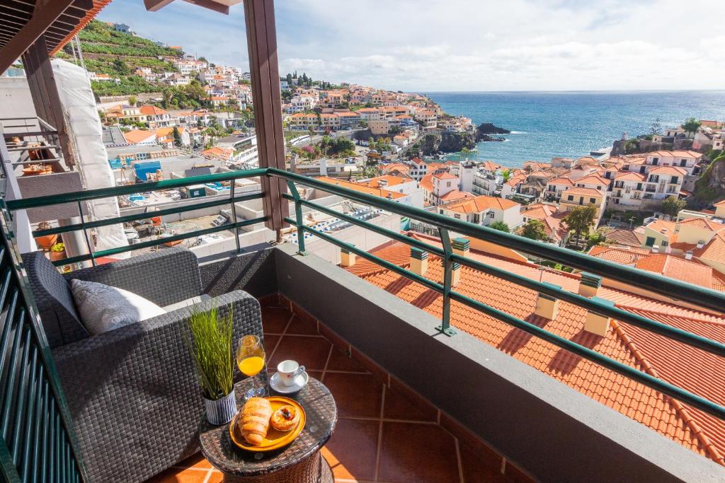 a balcony with a table and a view of the ocean at Villa Lobos Flat 1 in Câmara de Lobos