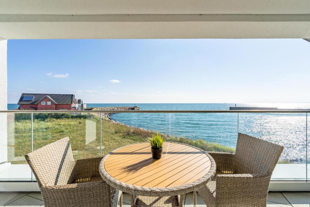 a table and chairs on a balcony with a view of the ocean at Ferienwohnung Seeloge im Bollwark Olpenitz in Olpenitz