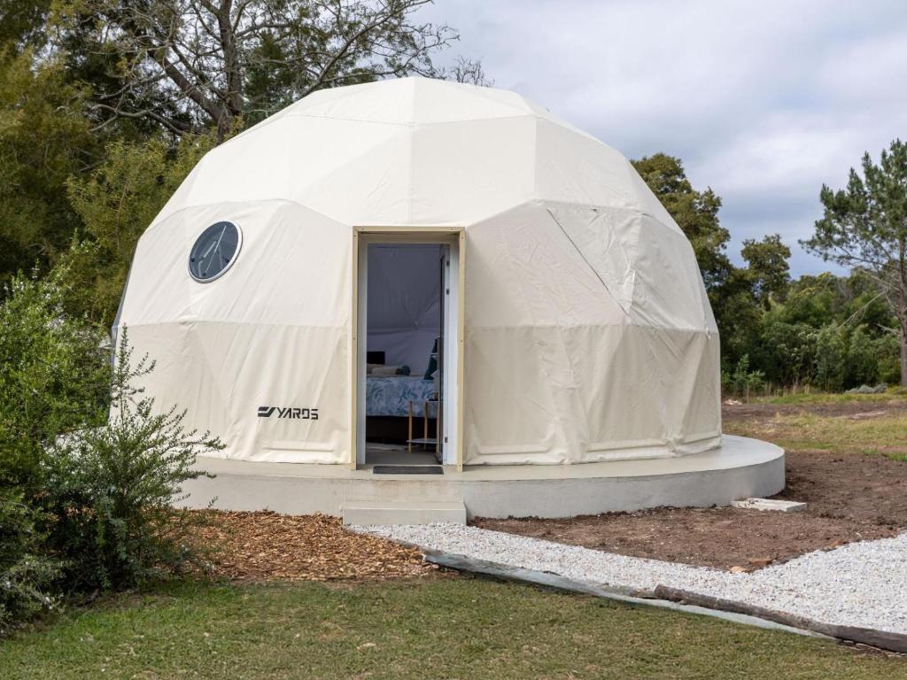 a white dome tent with a door in a field at Five Elements Resort - Dome Glamping Tent in Harkerville