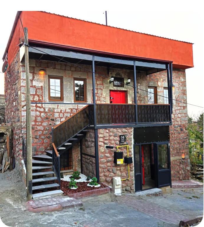 a brick building with a staircase and a red door at MiNKA HOUSE in Hisarcık