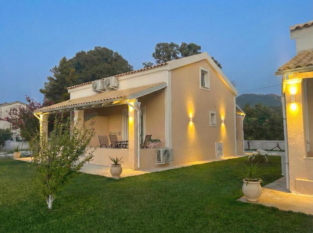 a white house with lights on a yard at Hestia ApartHotel in Roda