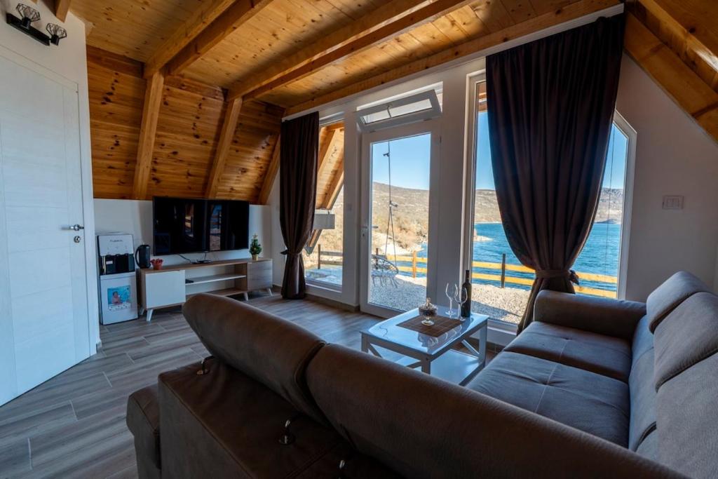a living room with a couch and large windows at Apartmani Janjusevic 2 in Mali Zakrnjak