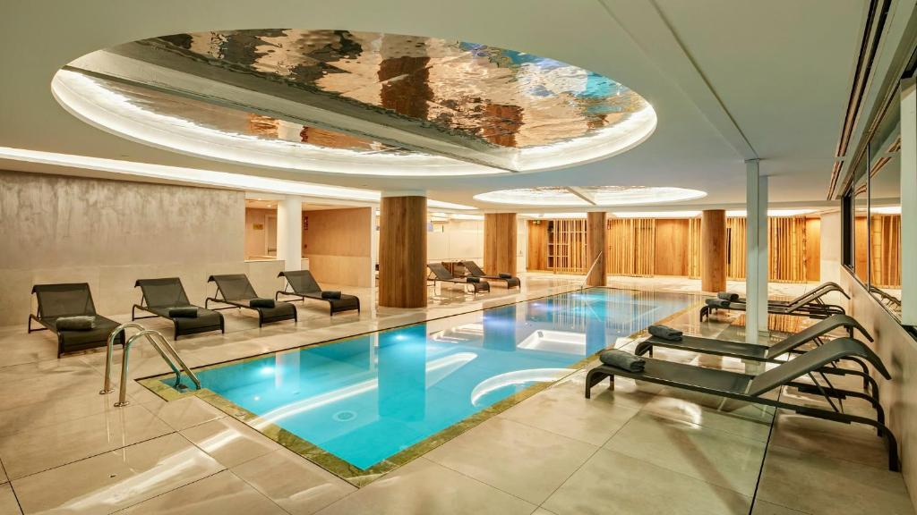 a large swimming pool with chairs and a ceiling at Sercotel HMO Martina in Granada
