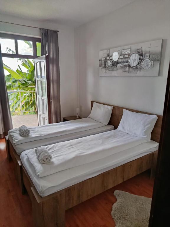 two beds sitting in a room with a window at Panoráma apartman in Pécs
