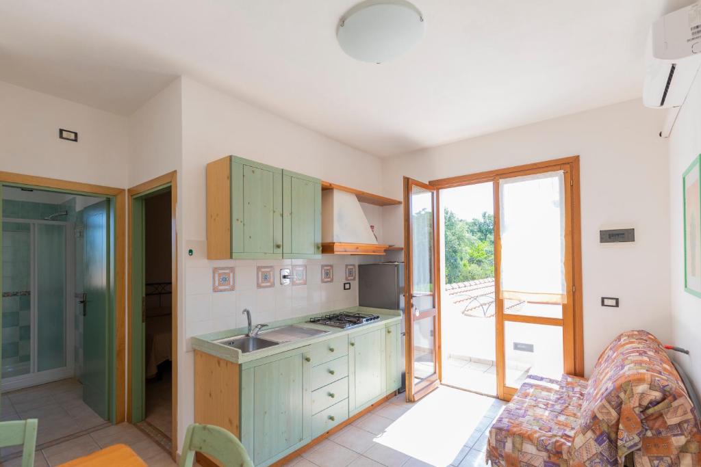 a kitchen with green cabinets and an open door at Villa Le Palme 3 - 4 in Casa Buraccio