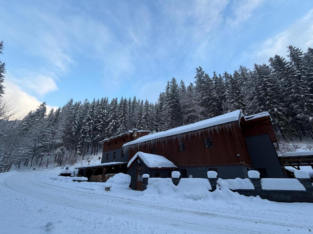 a barn covered in snow next to a road at Kamenný Mlýn in Strážné