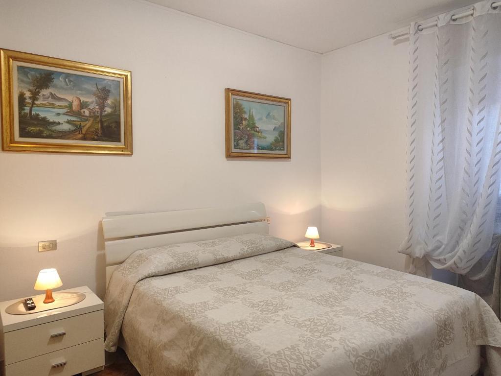 a white bedroom with a bed and two lamps at Margherita in Seriate