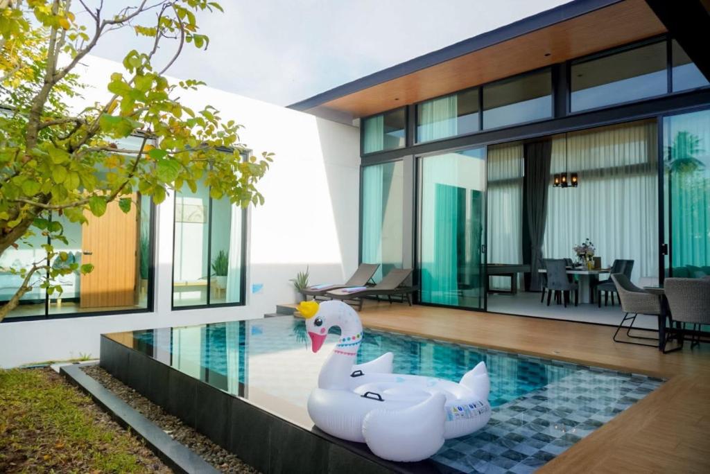 a house with a swimming pool with two inflatable swans at บ้านไร่มีสุข Baanrai Meesuk in Suratthani