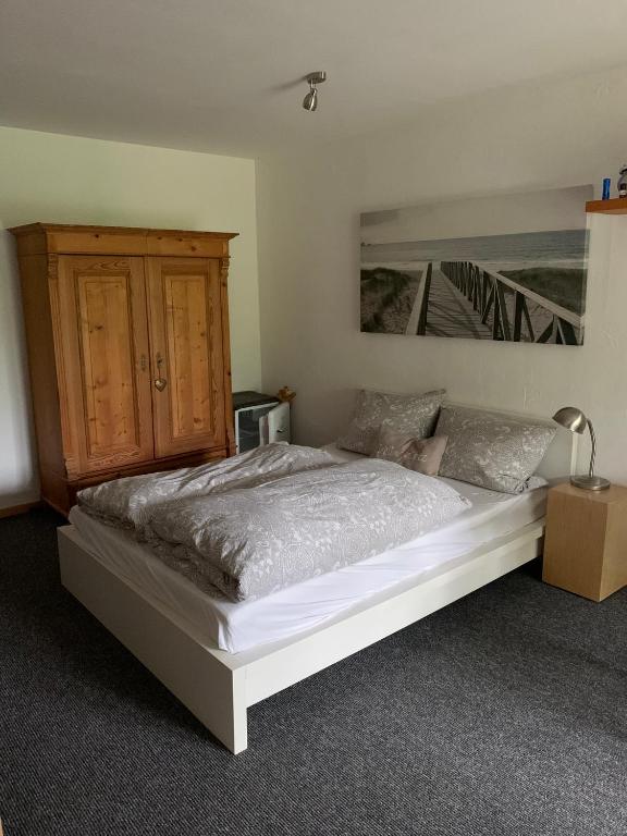 a bedroom with a bed and a wooden cabinet at Souterrain Appartment, eigene Dusche u WC in Detmold