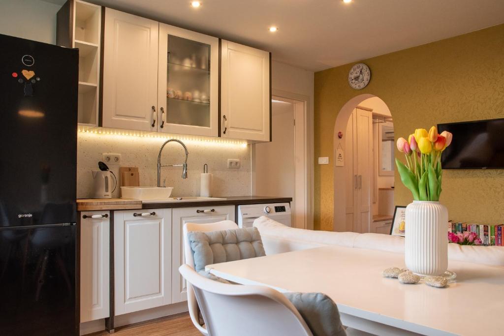 a kitchen and living room with a white table with tulips at Little Oasis Apartment in Zgornje Gorje
