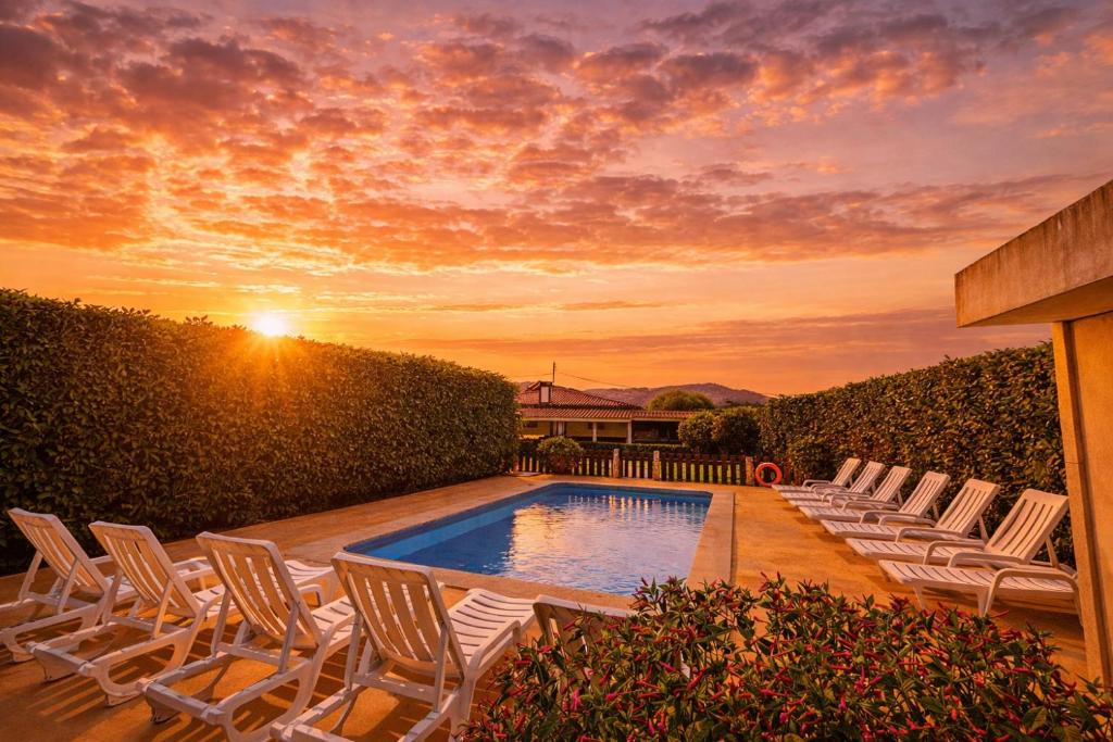 a group of chairs and a swimming pool with the sunset at Casa Antigo Alambique in Santa Cruz do Lima
