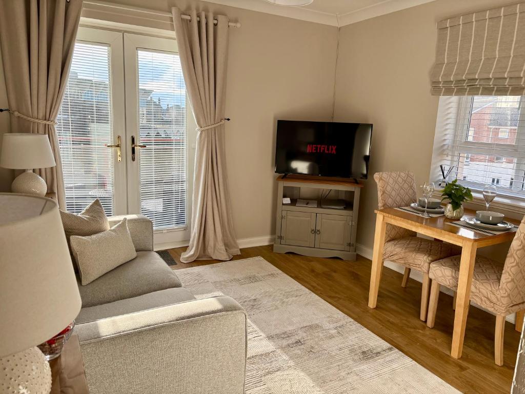 a living room with a couch and a table and a tv at Kincraig Apartment in Ayr