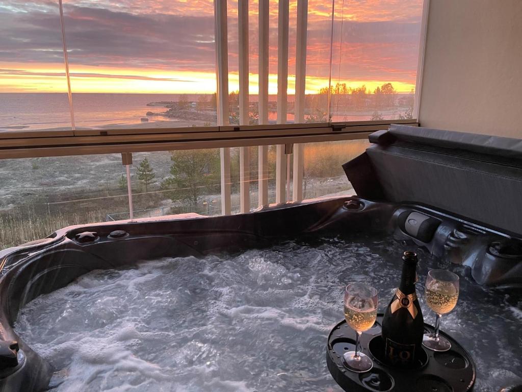 a hot tub with two glasses of wine in a room at Marina Resort A9 in Kalajoki