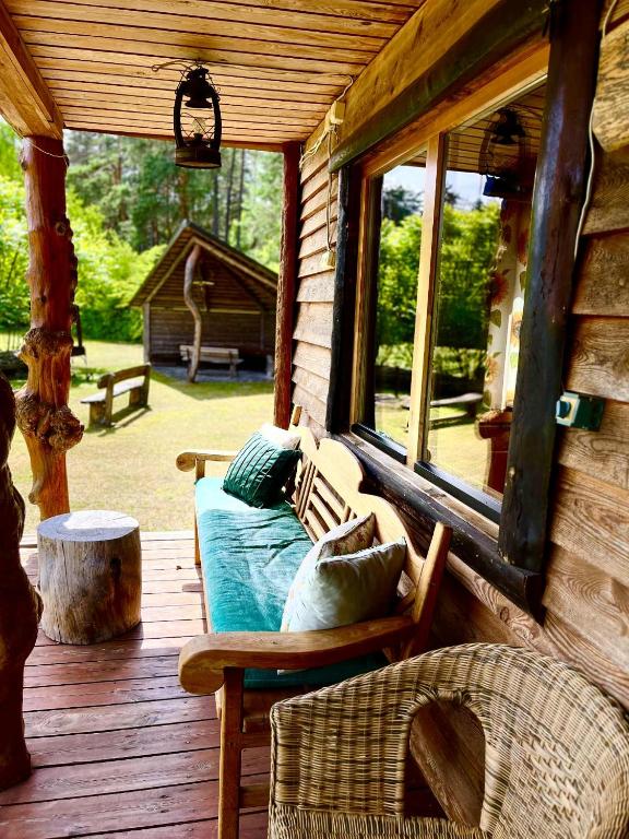 a porch of a log cabin with a couch and a window at Namelis Bitidė, sodyba Latkrantė, Druskininkai in Latežeris