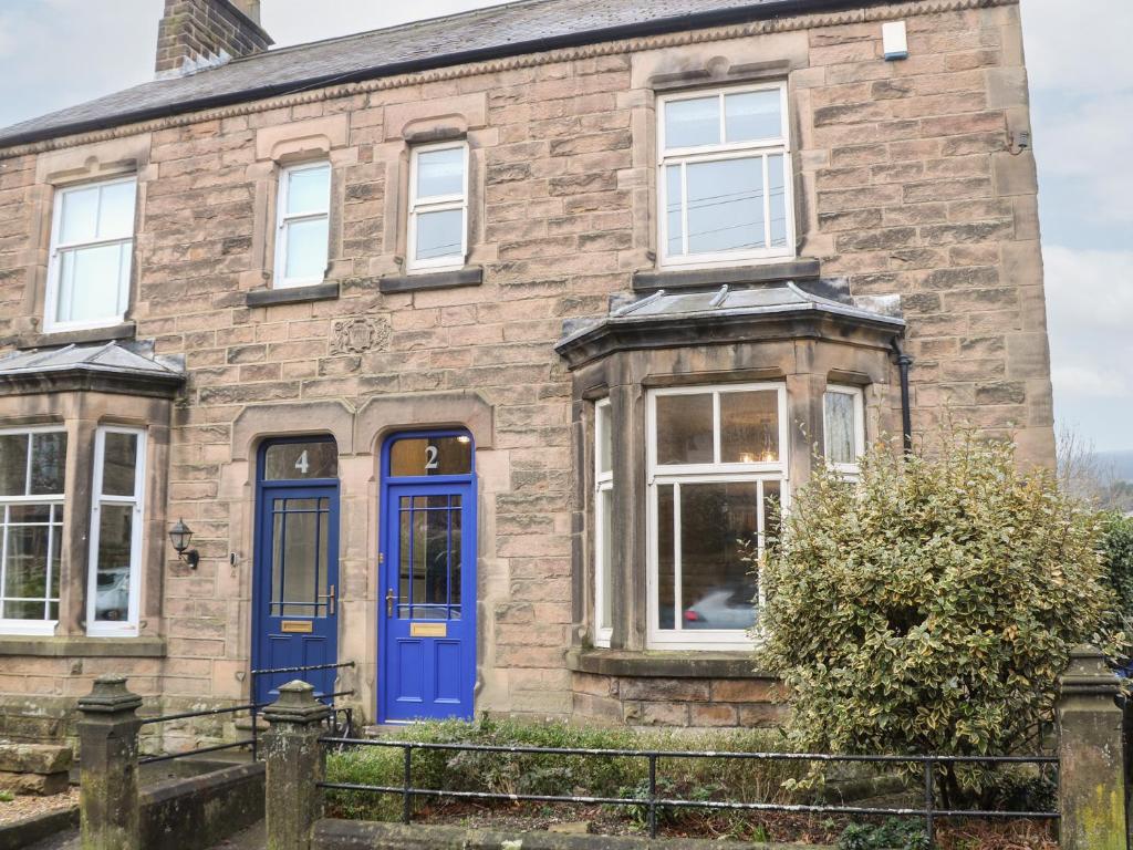an old stone house with blue doors and windows at Dorset Villas in Matlock