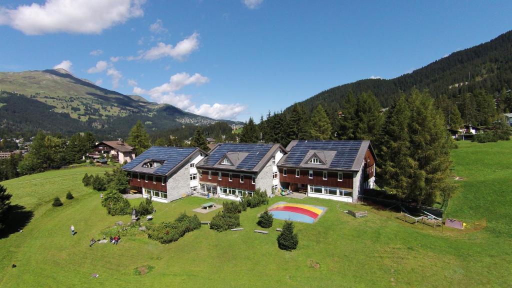 a large house with a rainbow on a green field at juhui Lenzerheide in Lenzerheide