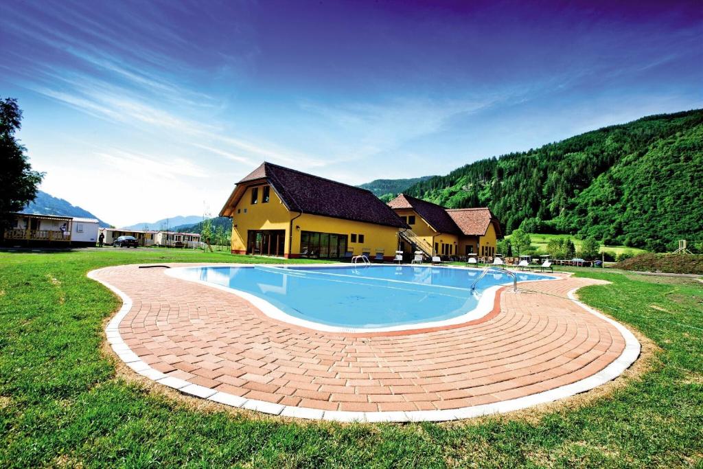 a swimming pool in a yard next to a house at Camping Bella Austria - Maeva Vacansoleil in Sankt Peter am Kammersberg
