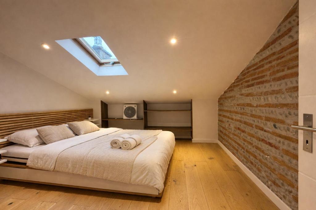 a bedroom with a bed and a brick wall at Cocon Mansardé - Velux et Clim - Hyper Centre in Toulouse