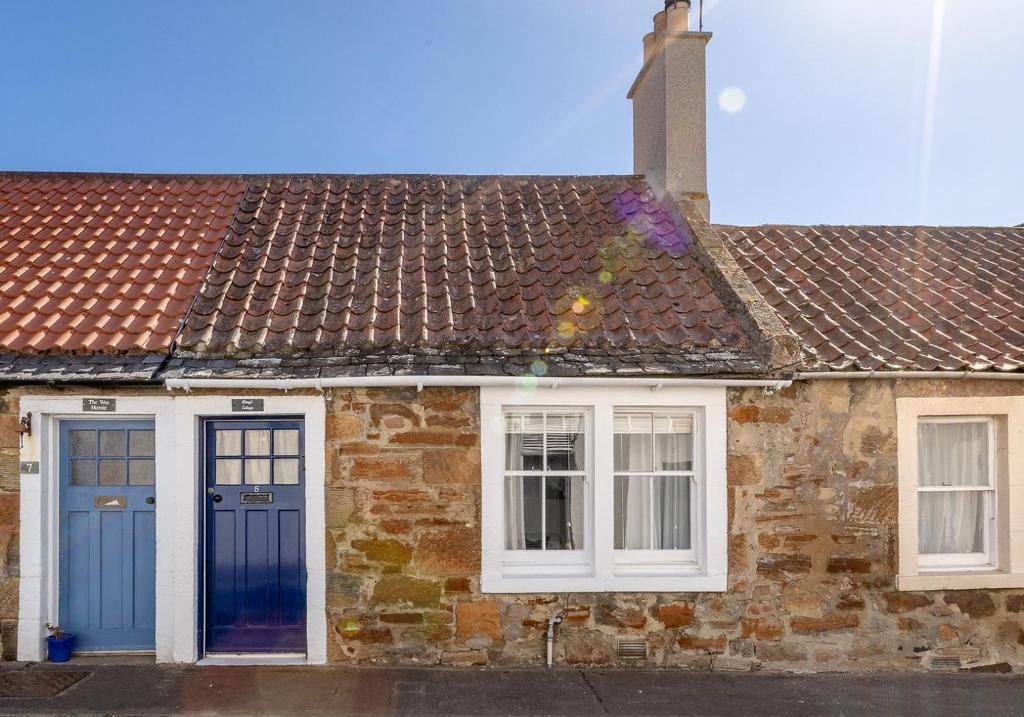 a brick house with blue doors and windows at Doug's Cottage in Elie