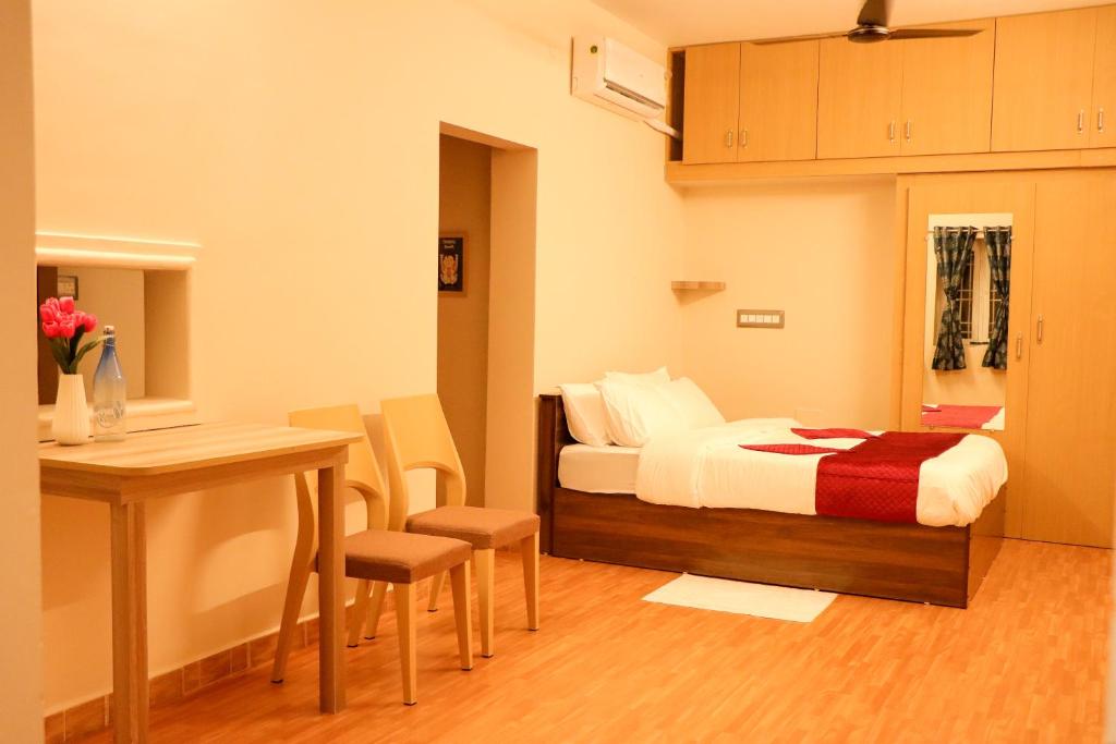 a bedroom with a bed and a table and a desk at Le Sara's Nest in Pondicherry