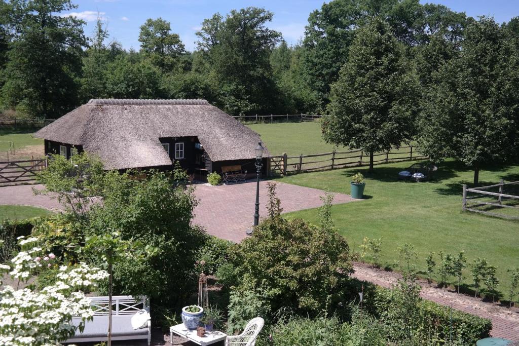 a house with a thatched roof in a garden at Schaapskooi in Maarsbergen