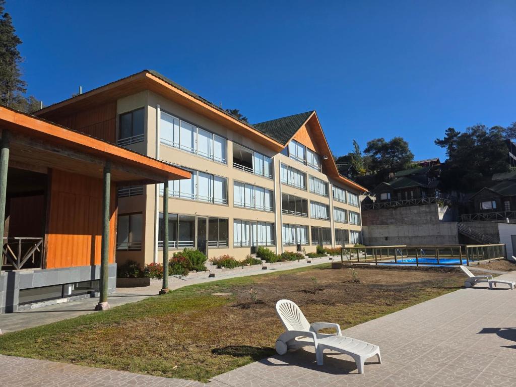 a white chair sitting in front of a building at Departamento Lago Vichuquen in Vichuquén Lake