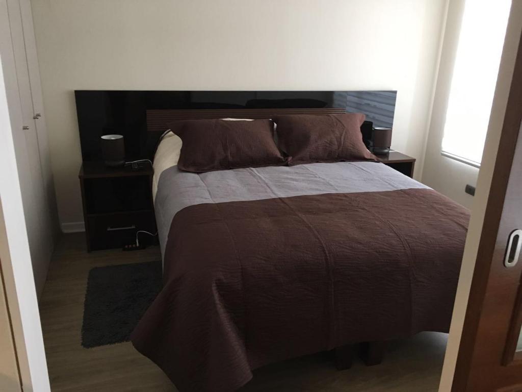 1 dormitorio con 1 cama con edredón marrón en Santiago Bus Terminal, en Santiago