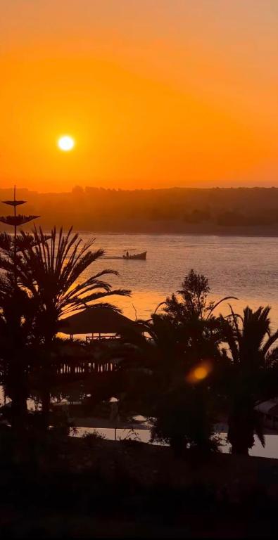 a sunset on a beach with a boat in the water at La terasse vue sur mer uniquement les familles in Oualidia