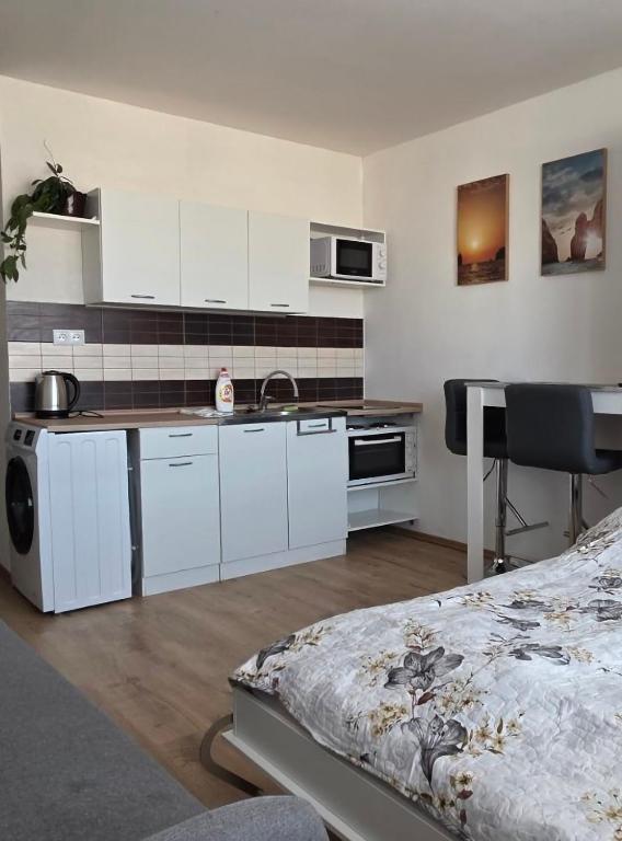 a kitchen with white cabinets and a table and a bed at Apartmán Horizont Martin-Sever in Martin