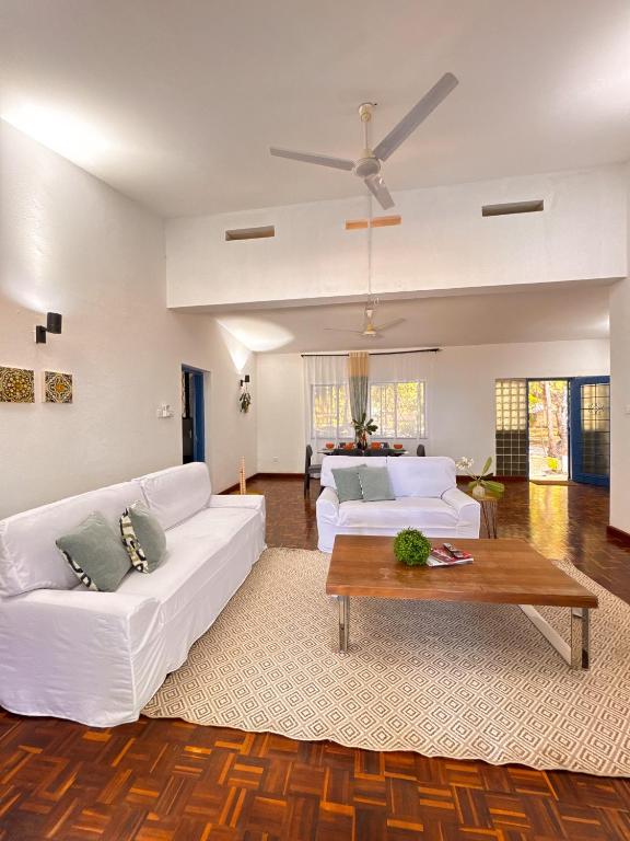 a living room with two white couches and a table at Attalah Beach Cottage in Mombasa