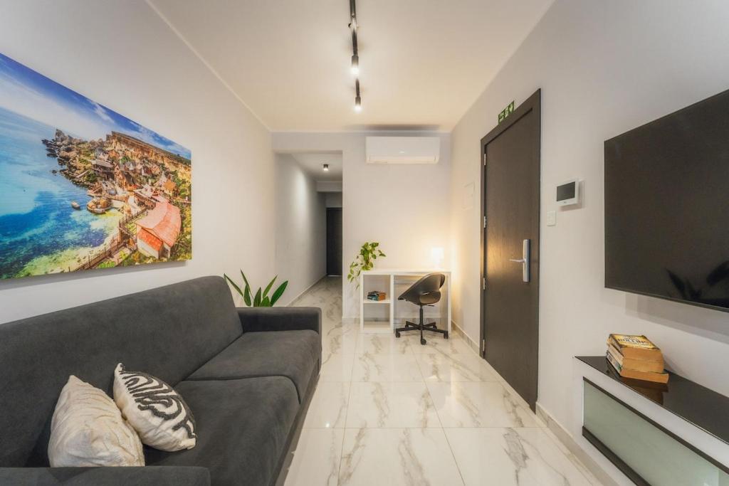 a living room with a couch and a flat screen tv at NEW - Only Suites Unit 6 - Modern 2-Bedroom apartment with common heated Jacuzzi by SF Homes in St. Julianʼs