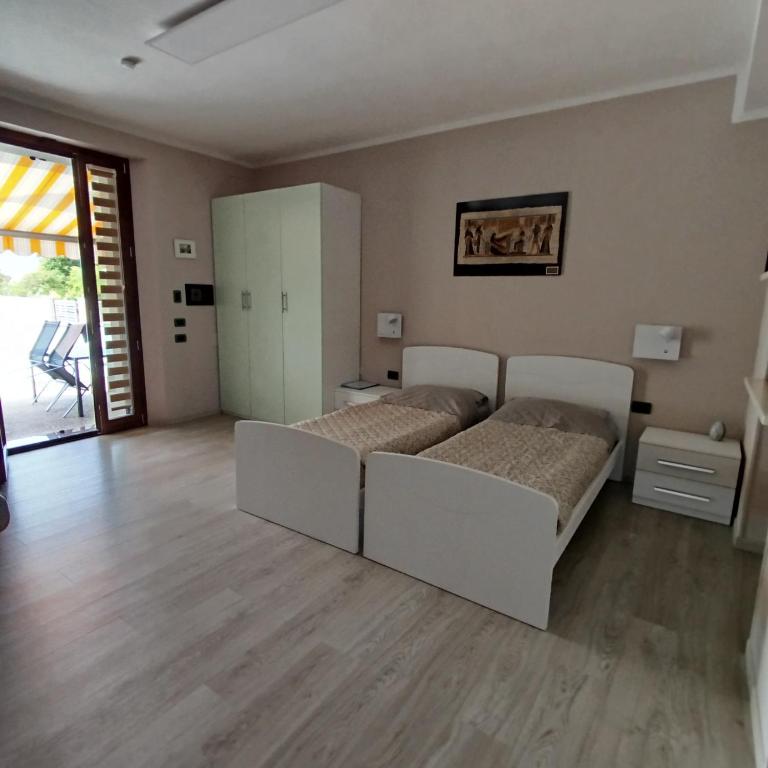 a bedroom with two beds and a sliding glass door at Casa Rossy in Pieve San Giacomo