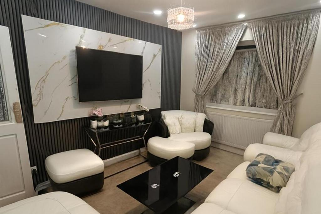 a living room with a television and white furniture at House-Sleeps 5 person -Etihad Stadium 15 min drive in Ashton under Lyne