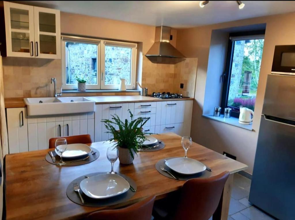 a kitchen with a wooden table with plates and wine glasses at Le Clos du Cerf - Le Sous-bois in Stoumont