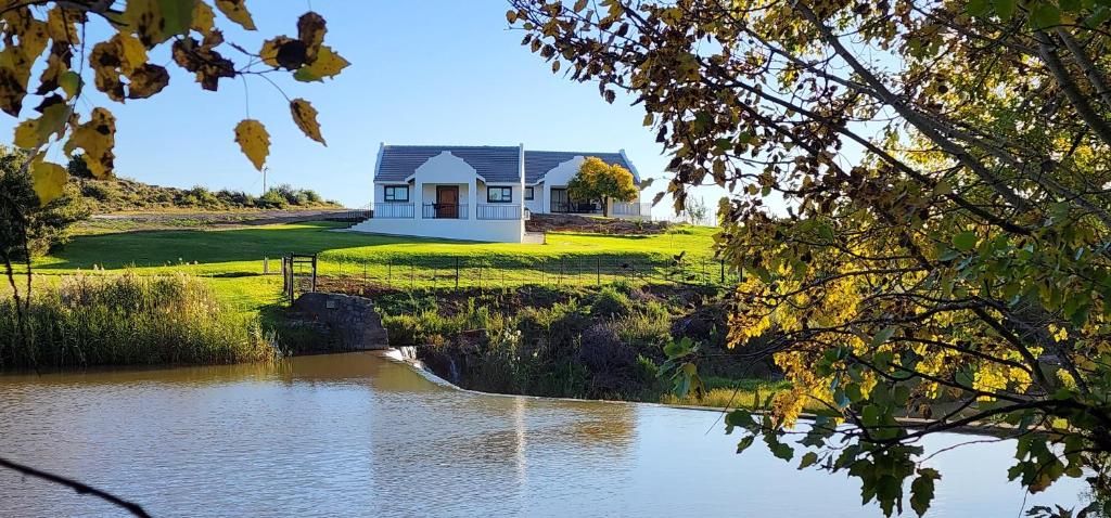 a house on a hill next to a body of water at Ongersfontein gasteplaas in Richmond