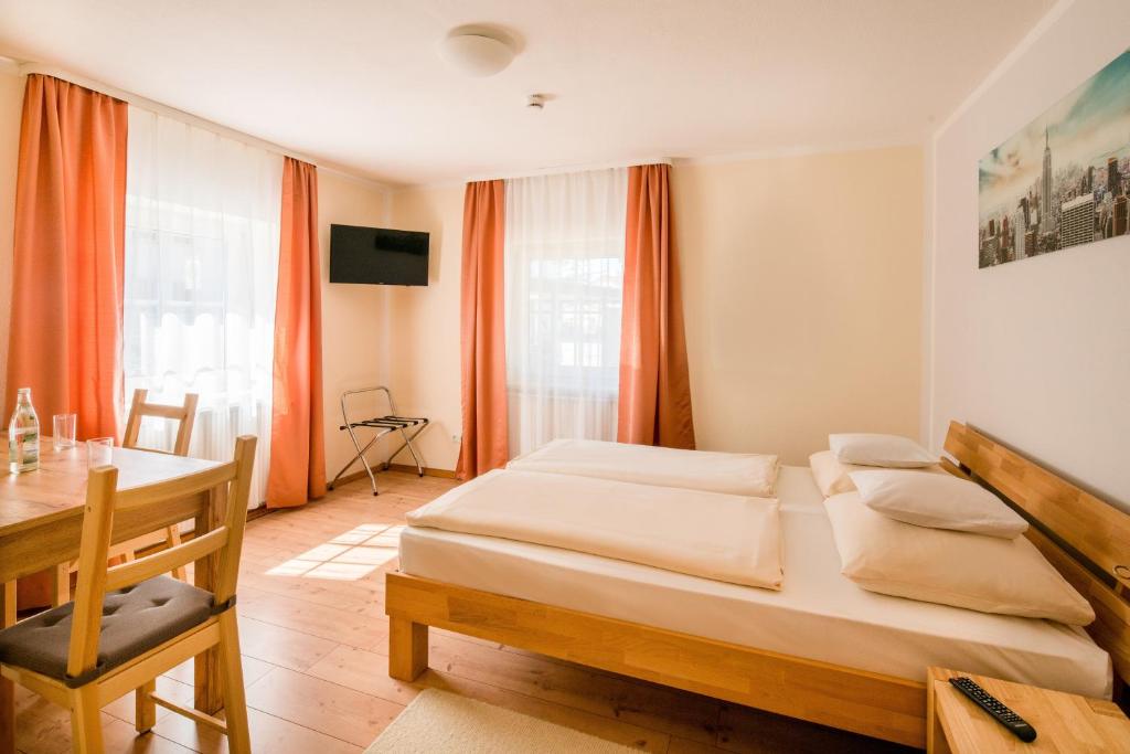 a bedroom with two beds and a table and a desk at WG-Pension in Landshut