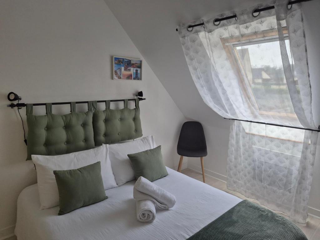 a bedroom with a bed with a green headboard and a window at Chez Ninie in Le Cloître-Saint-Thégonnec
