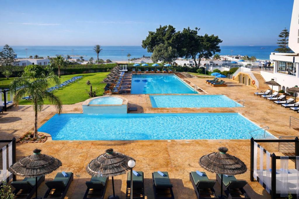 a large swimming pool with chairs and umbrellas at Anezi Tower Hotel in Agadir