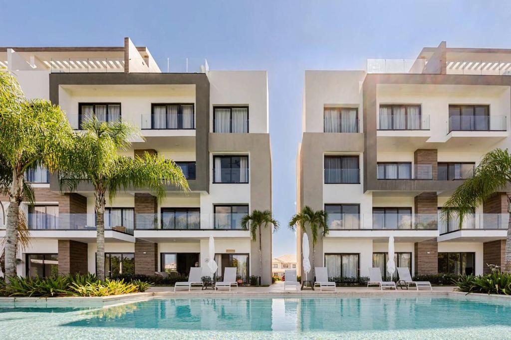 a hotel with a swimming pool in front of two buildings at Cana Cove in Punta Cana
