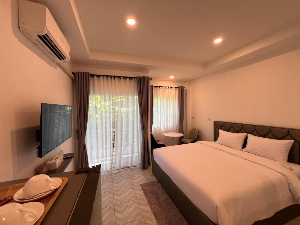 a hotel room with a bed and a television at Sarona House 3 in Ban Thalat Choeng Thale