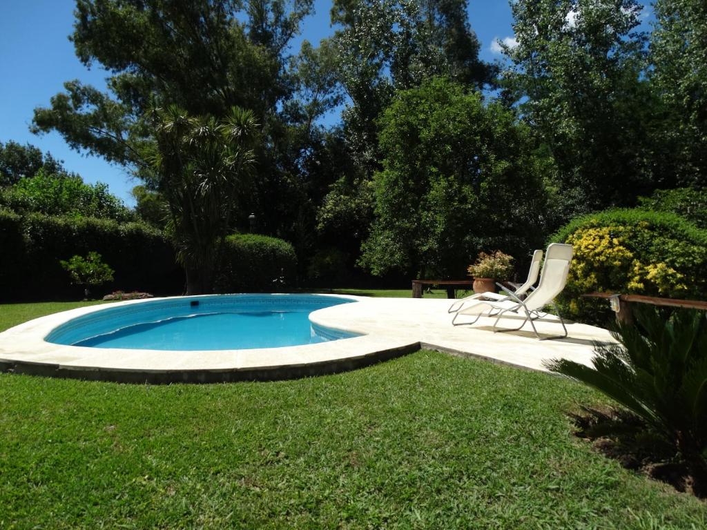 a swimming pool in a yard with two lawn chairs at La Rosa de los Vientos km54 in Belén de Escobar