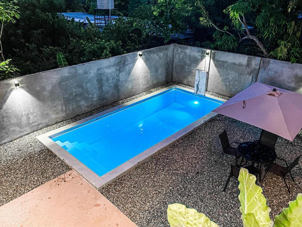 a swimming pool with an umbrella next to a chair at Casa Solaje in Brisas de Zicatela