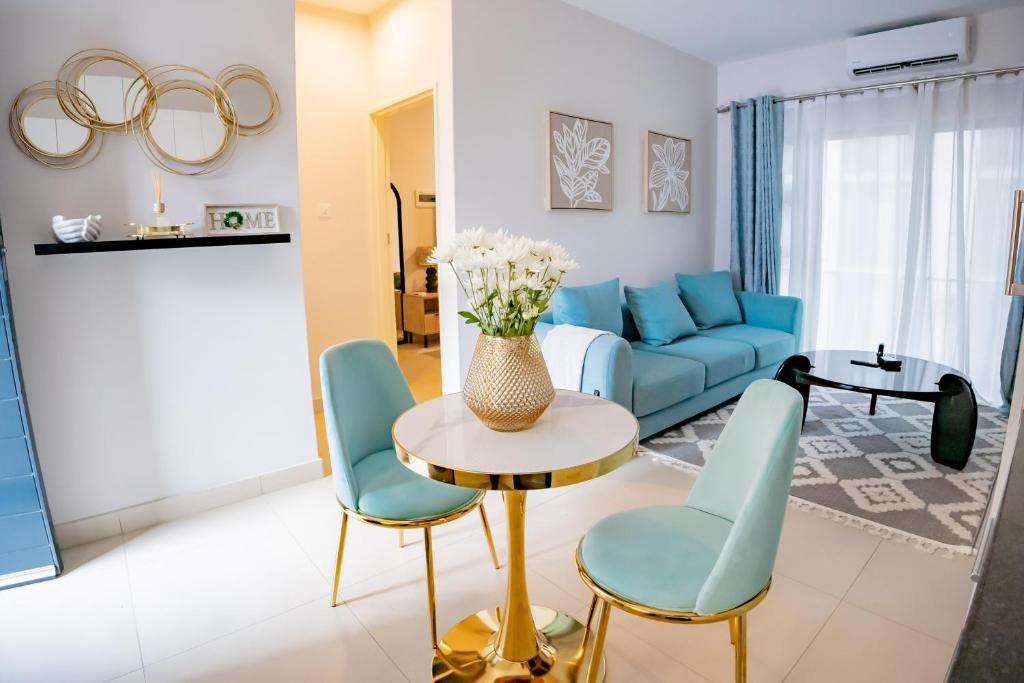a living room with a blue couch and a table and chairs at Lerako Apartment in Gaborone