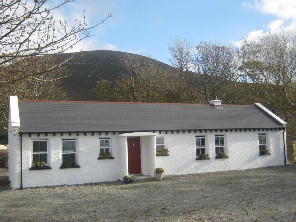 a white house with a mountain in the background at Rural Donegal cottage near sandy beaches in Clonmany