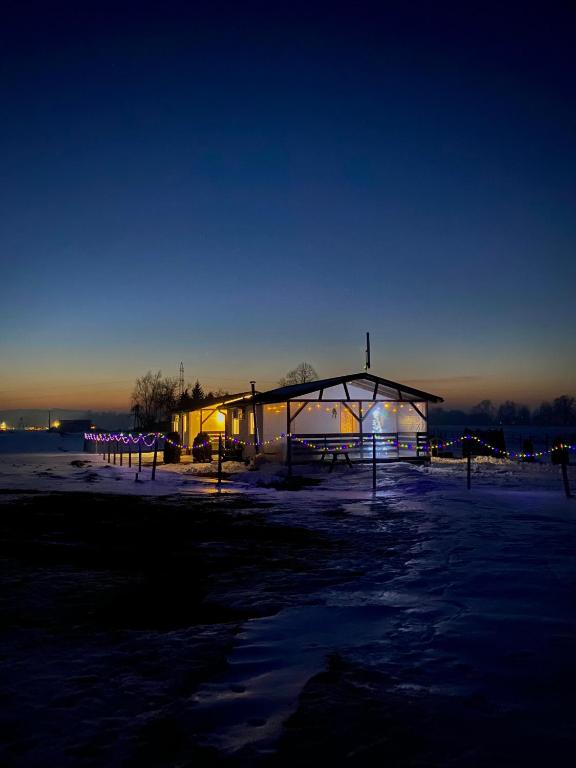 a lit up building in the snow at night at Zacisze nad wodą in Strzegocice